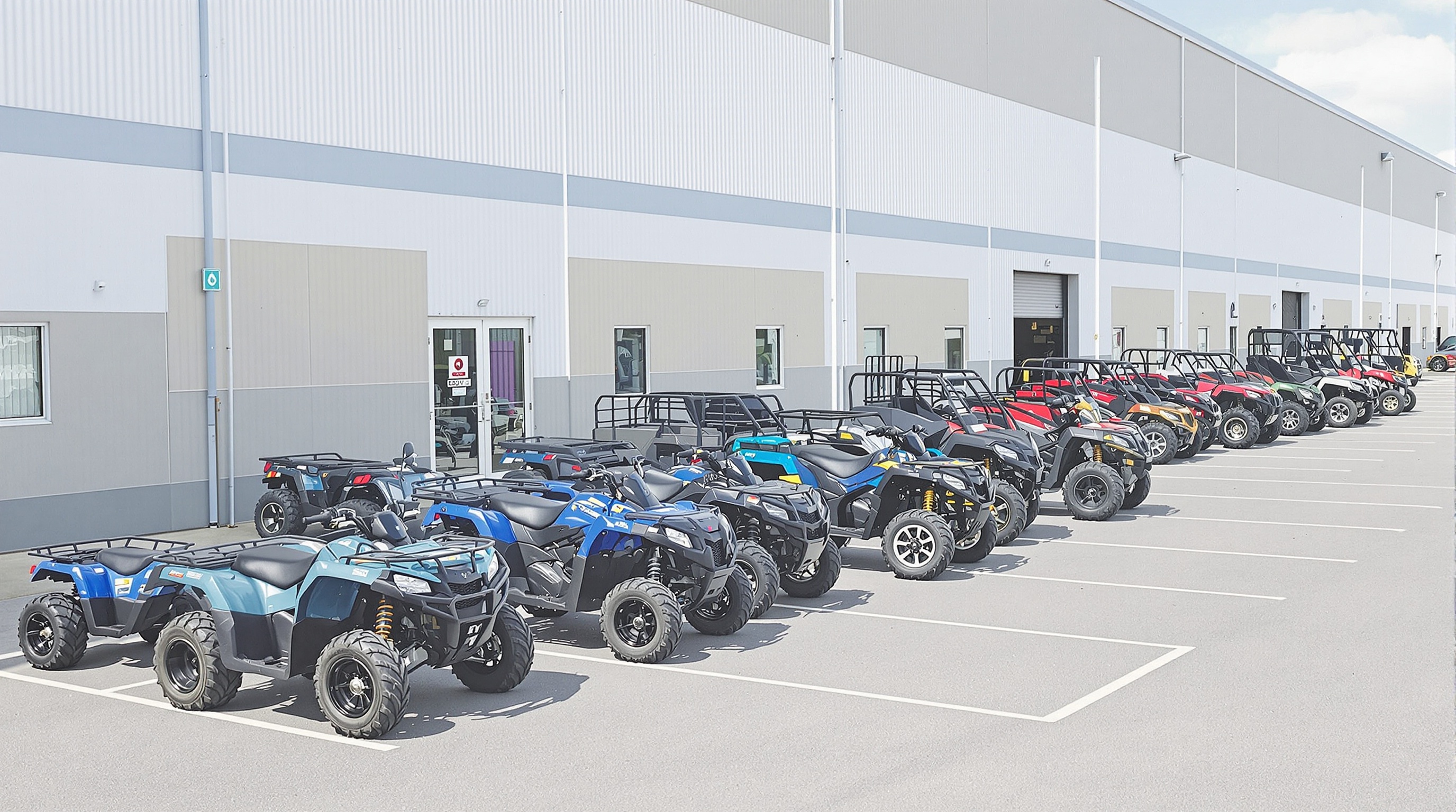 Comparatif visuel de modèles de quads neufs, alignés sur un parking, du 50cc au SSV