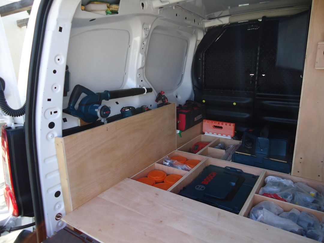 Un fourgon professionnel chargé de matériel divers, montrant l'intérieur bien organisé avec des outils et des équipements.