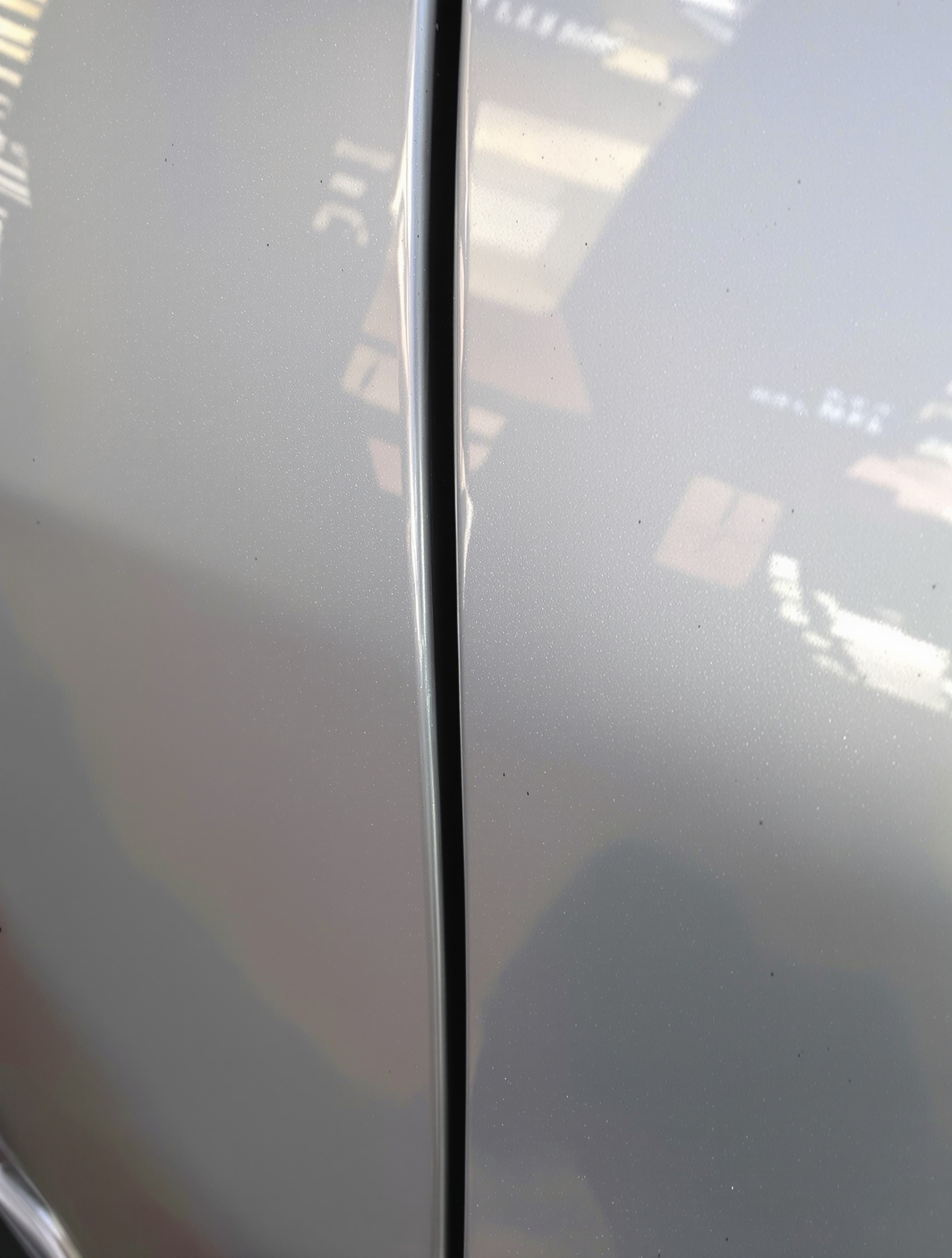 Gros plan sur une portière de voiture d'occasion présentant une légère différence de teinte, signe potentiel d'une réparation mal effectuée.