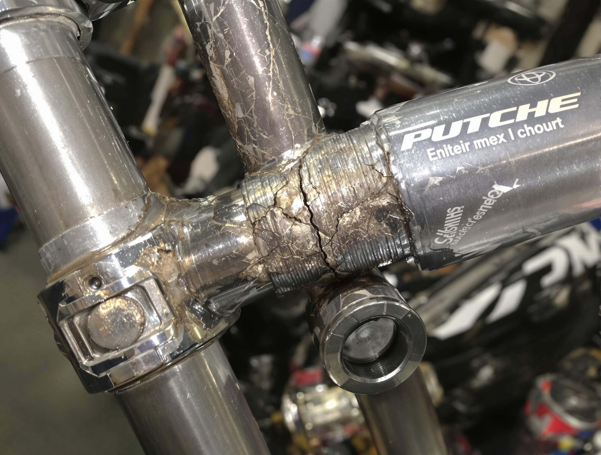 Gros plan sur une soudure suspecte au niveau de la colonne de direction d'un cadre de moto cross, illustrant un point de contrôle crucial à vérifier lors de l'inspection avant une enchère.